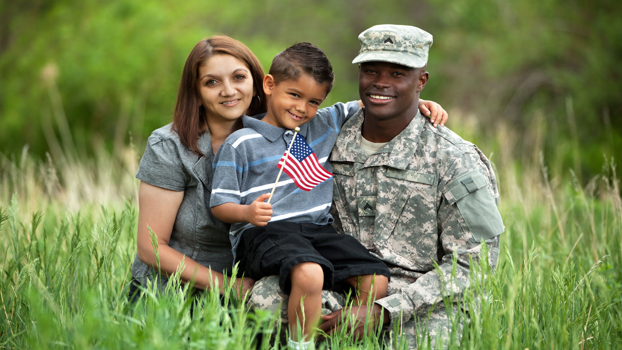 A man in fatigues and a woman holding a boy.