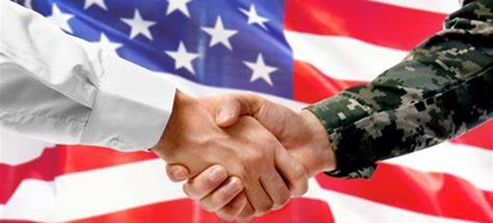 Two people shaking hands in front of an american flag.