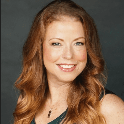 A woman with long red hair and wearing a necklace.